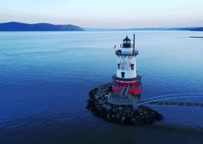 Tarrytown lighthouse in the early morning light, with the Hudson River surrounding and Palisades in the distance.