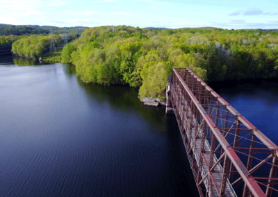 An aerial view of the railway bridge portion of the North County Trailway, over the Croton Reservoir, with the woods and hills in the background.