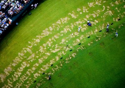 Aerial View of Practice Tee, US Open, showing worn patches of grass, golfer and stands.